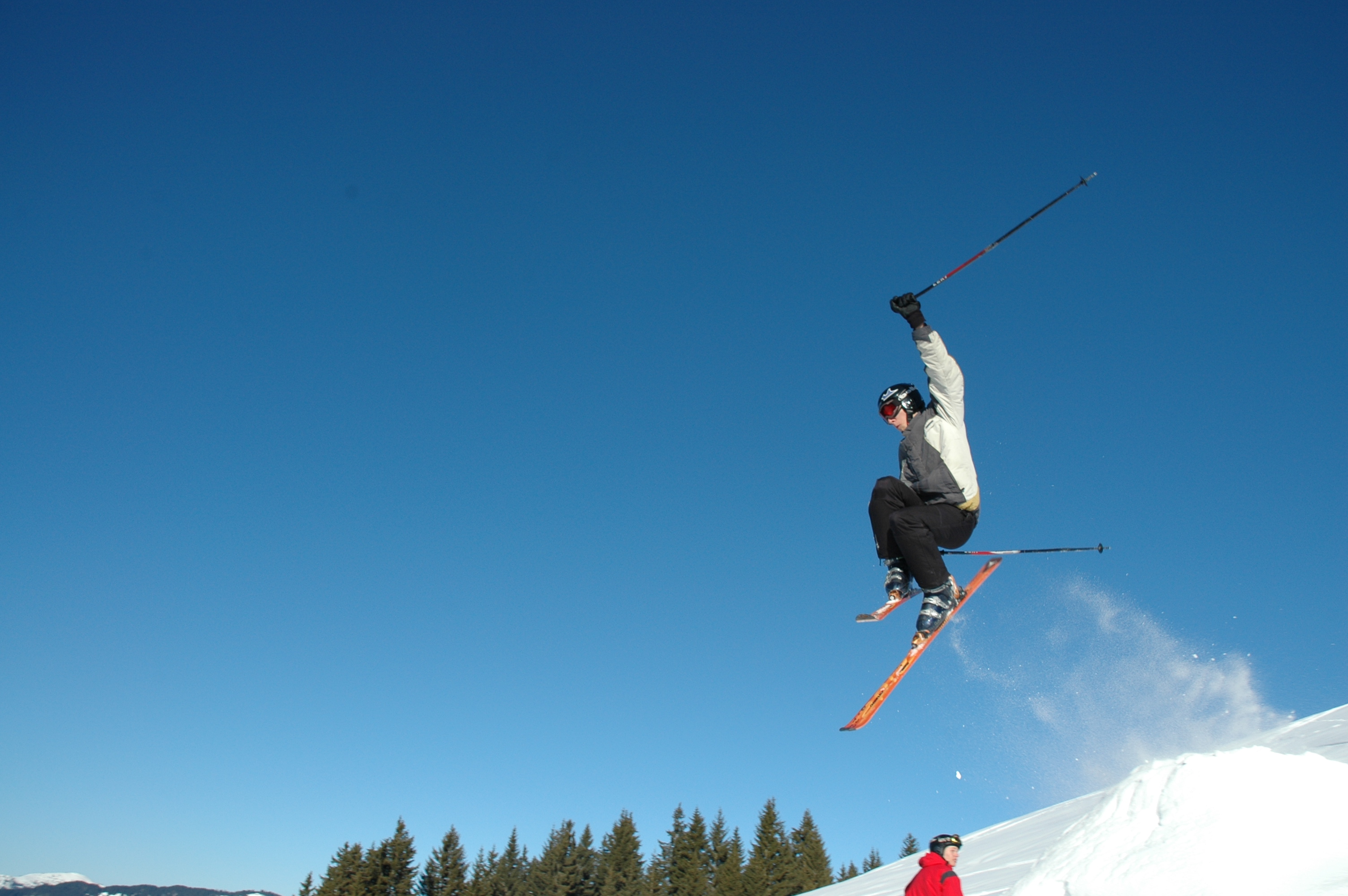 Ein Skifahrer springt auf der Schipiste in die Luft.