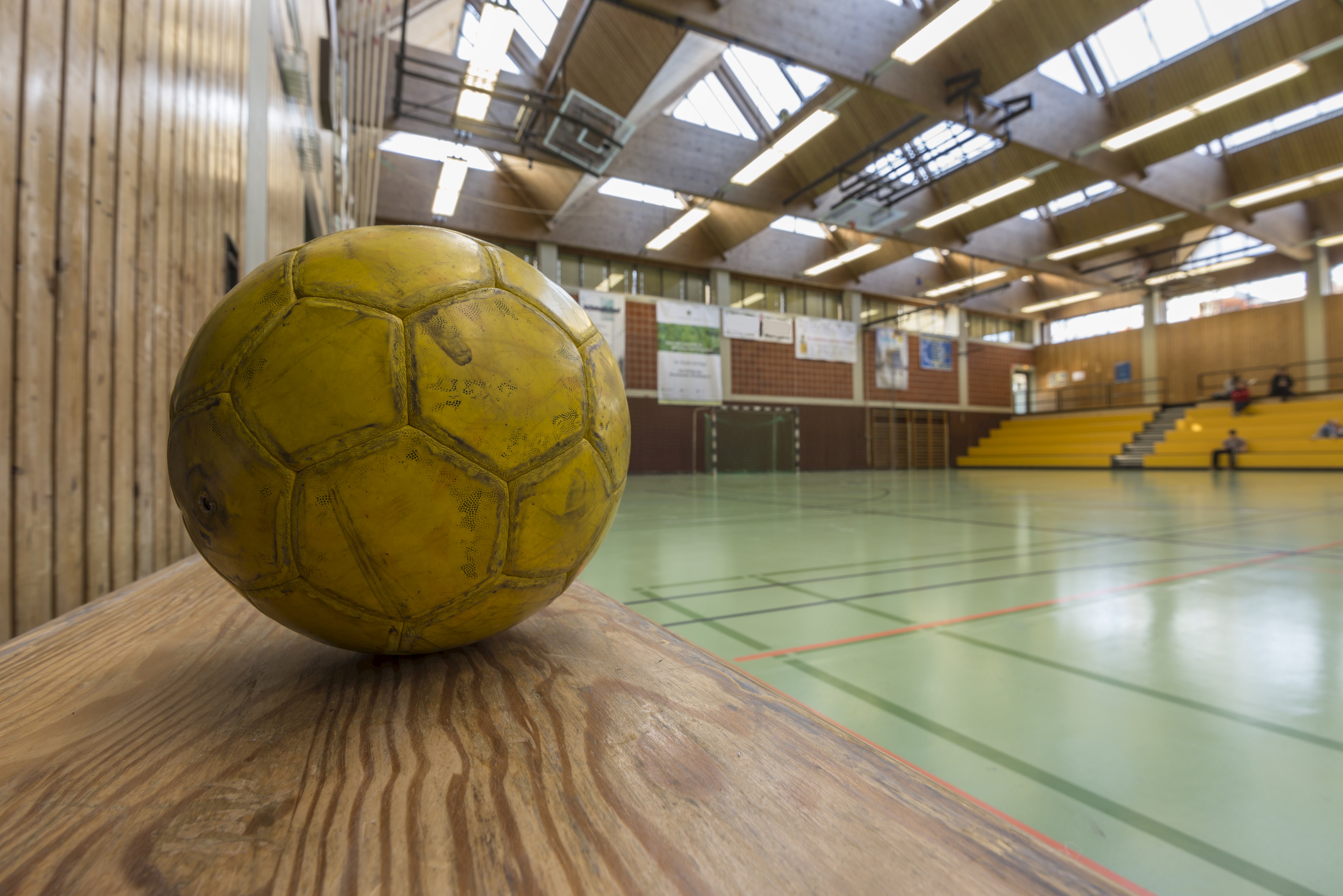 Gelber Fussball in einer leeren Sporthalle